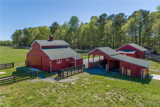 exterior space featuring a chimney, a barn, a carport, and an outbuilding