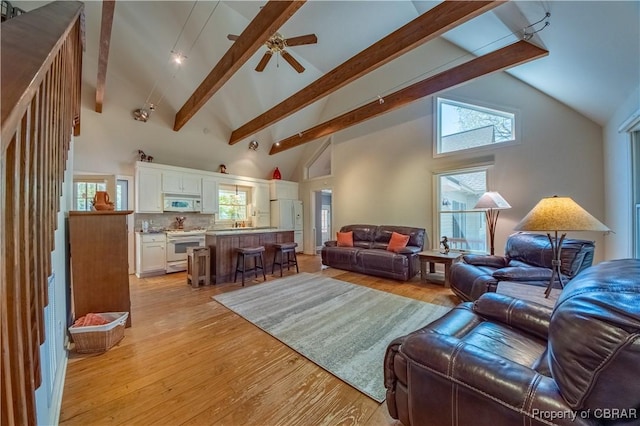 living room with beamed ceiling, high vaulted ceiling, light wood-type flooring, a ceiling fan, and plenty of natural light