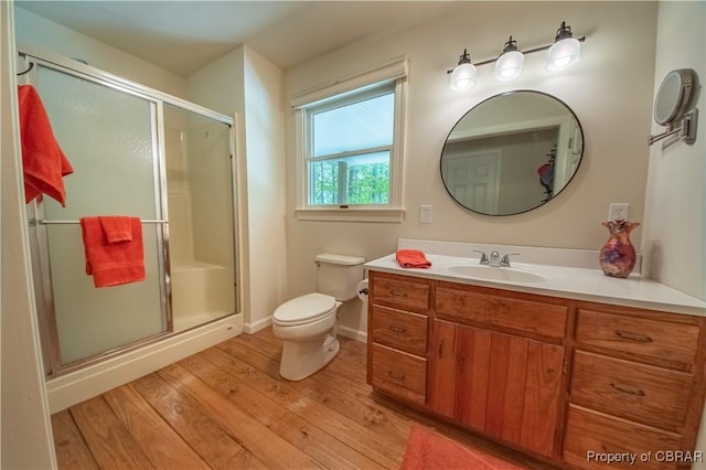 bathroom with a shower stall, vanity, toilet, baseboards, and wood finished floors