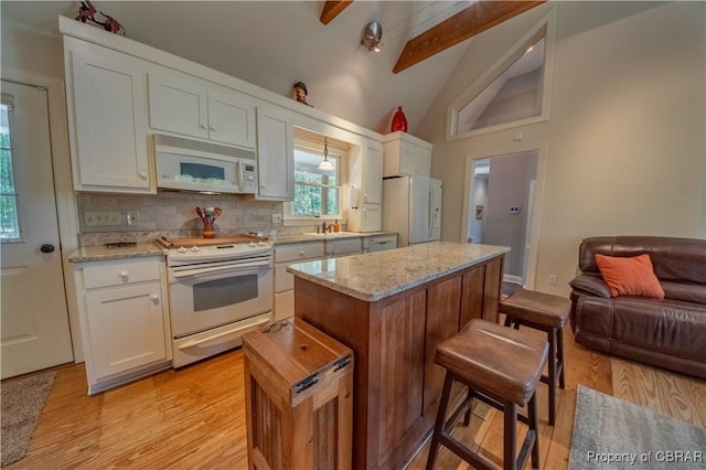 kitchen with a sink, a kitchen bar, light wood-type flooring, white cabinetry, and white appliances