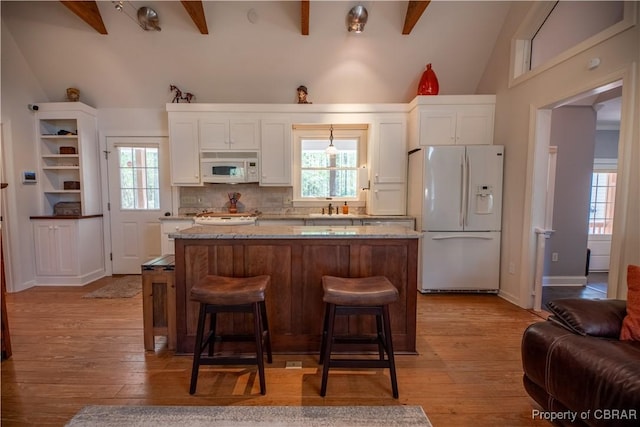 kitchen with light wood finished floors, white appliances, white cabinets, and a center island