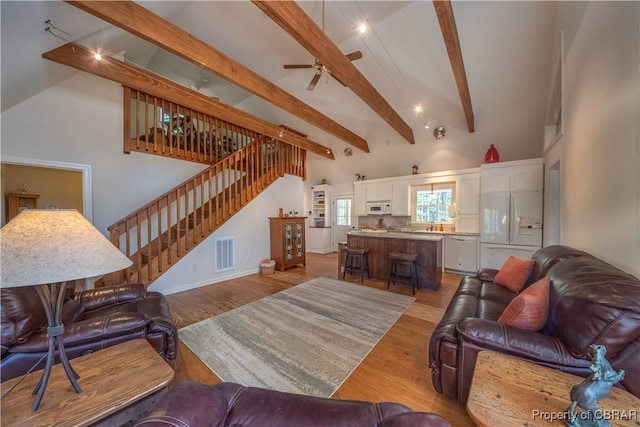 living room with light wood-style flooring, stairway, visible vents, beam ceiling, and a ceiling fan