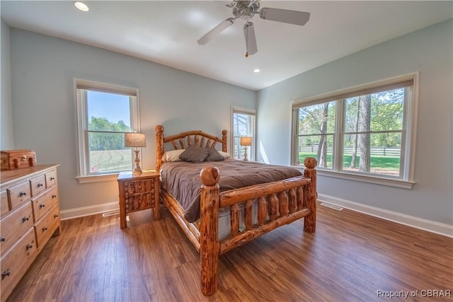 bedroom with multiple windows, wood finished floors, visible vents, and baseboards