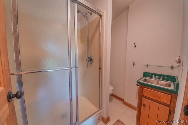 bathroom featuring baseboards, a shower stall, toilet, and vanity