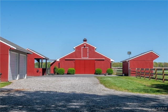 view of barn with fence and a yard
