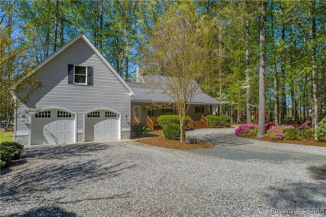 view of front of home with a porch, gravel driveway, and an attached garage
