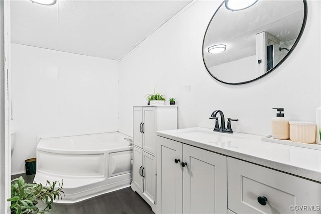 full bathroom with wood finished floors, vanity, and a bath