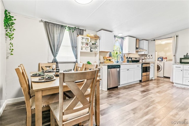 kitchen featuring light wood finished floors, white cabinets, stainless steel appliances, and washer and clothes dryer