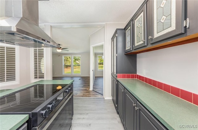 1223 Ullainee Rd, Essex, VA 22436 - kitchen with black range with electric stovetop, wall chimney range hood, light wood-type flooring, ceiling fan, and a textured ceiling