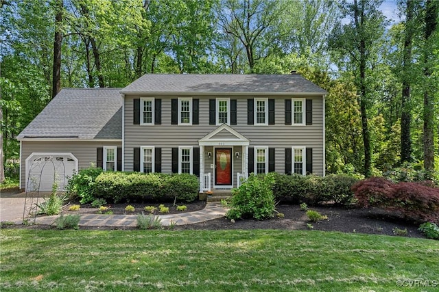 colonial home with a garage, driveway, and a front lawn