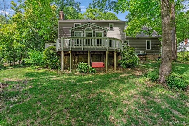 rear view of property featuring a chimney, a yard, and a deck