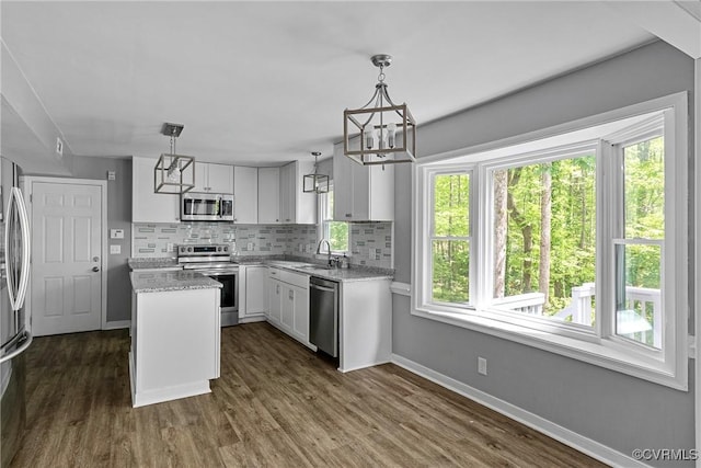 kitchen with a center island, white cabinets, a chandelier, tasteful backsplash, and stainless steel appliances