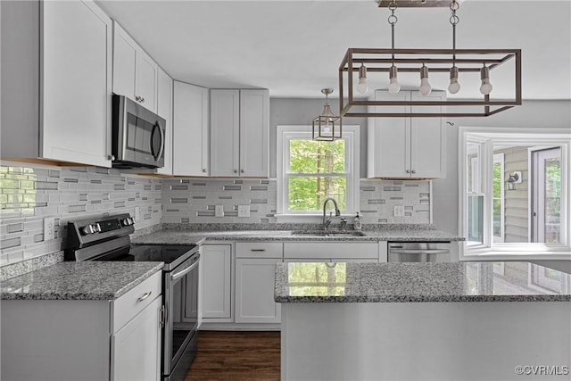 kitchen with decorative backsplash, light stone countertops, white cabinets, a sink, and stainless steel appliances