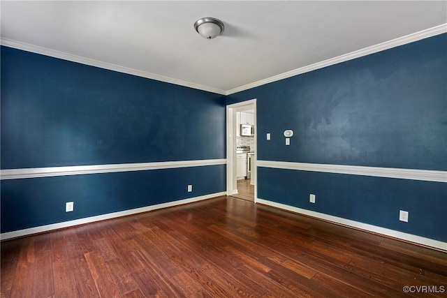 spare room with baseboards, ornamental molding, and wood finished floors