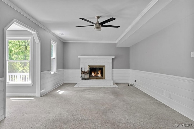 unfurnished living room with crown molding, carpet flooring, a brick fireplace, and a ceiling fan