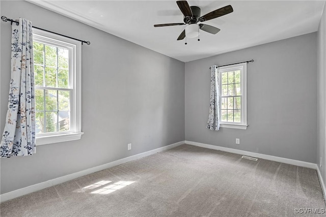 carpeted empty room with a ceiling fan, baseboards, and visible vents