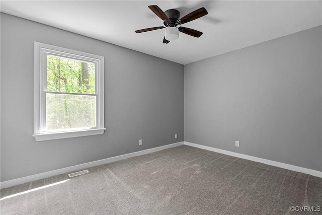 spare room with baseboards, a ceiling fan, dark carpet, and visible vents