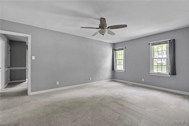 carpeted spare room with a ceiling fan and baseboards