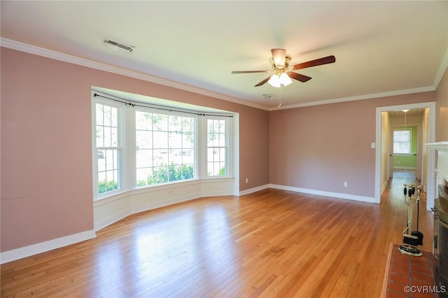 empty room featuring ceiling fan, visible vents, baseboards, ornamental molding, and light wood-style flooring