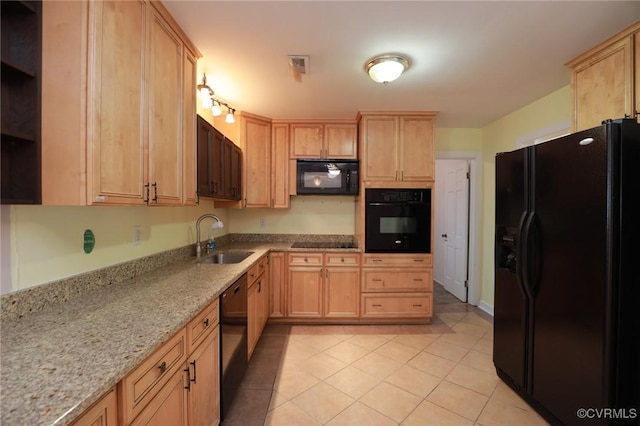 kitchen with light brown cabinets, light stone countertops, a sink, light tile patterned floors, and black appliances