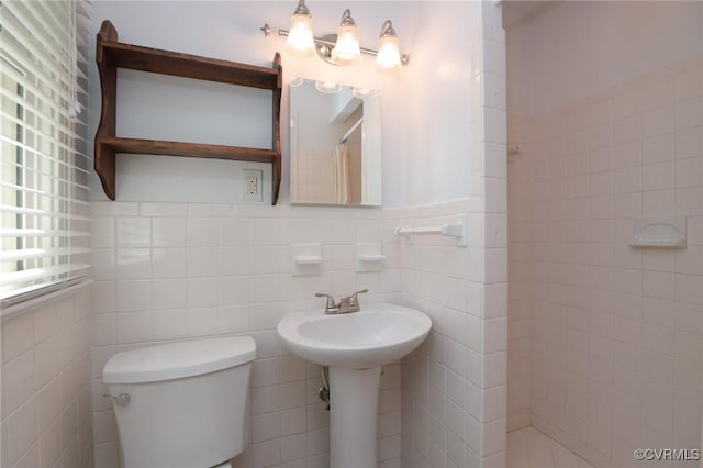 full bath featuring a tile shower, toilet, and tile walls