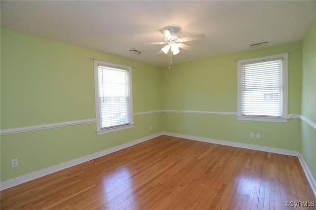 unfurnished room featuring ceiling fan, visible vents, baseboards, and hardwood / wood-style floors