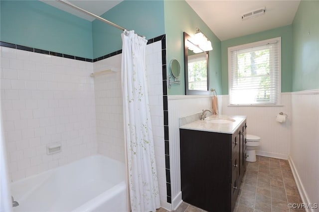 full bathroom featuring visible vents, a wainscoted wall, vanity, toilet, and shower / bath combo with shower curtain