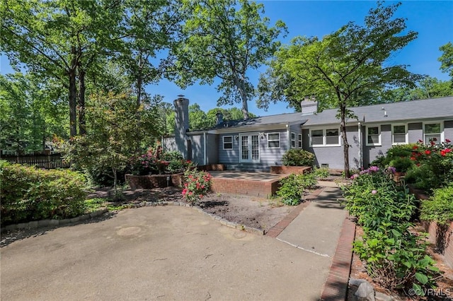 back of property with a patio, fence, french doors, and a chimney