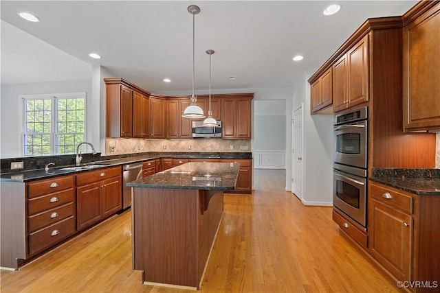 kitchen with light wood-style flooring, a sink, stainless steel appliances, a center island, and backsplash