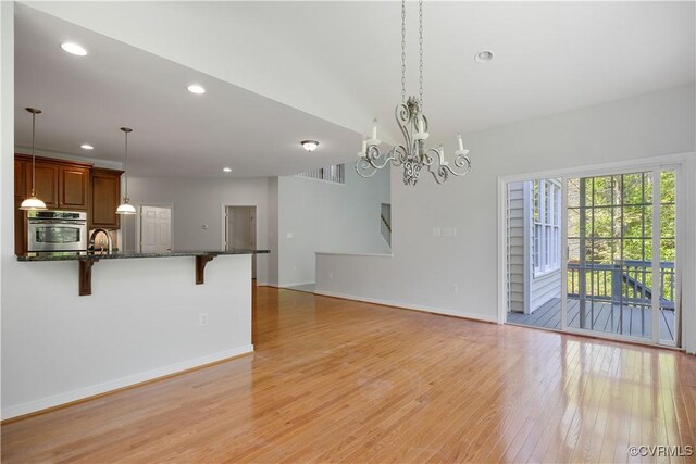 unfurnished living room featuring recessed lighting, a chandelier, light wood-style floors, a sink, and baseboards
