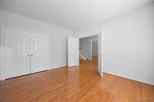 unfurnished bedroom with light wood-type flooring, a closet, and baseboards