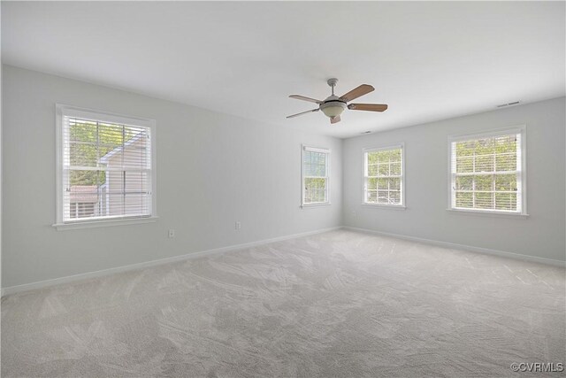 unfurnished room featuring baseboards, visible vents, a ceiling fan, and light colored carpet