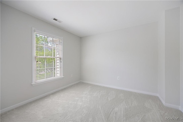 spare room with visible vents, light colored carpet, and baseboards