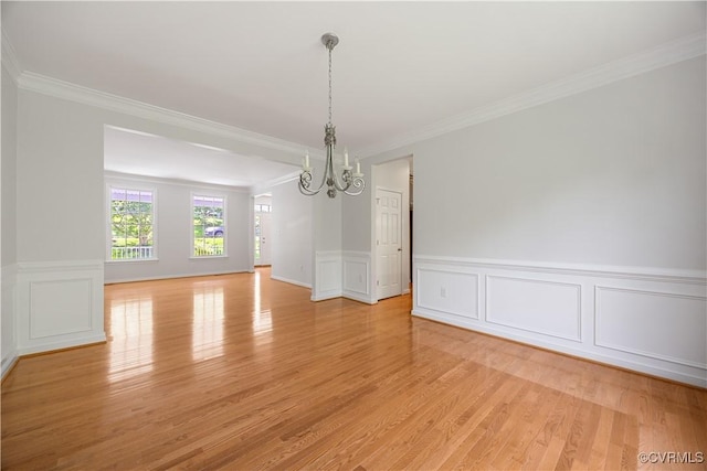 unfurnished dining area with crown molding, light wood finished floors, an inviting chandelier, and a decorative wall