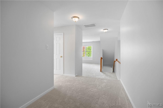hallway featuring baseboards, visible vents, an upstairs landing, and carpet flooring