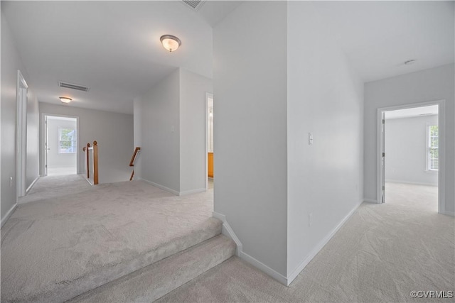 hallway featuring baseboards, visible vents, an upstairs landing, and carpet