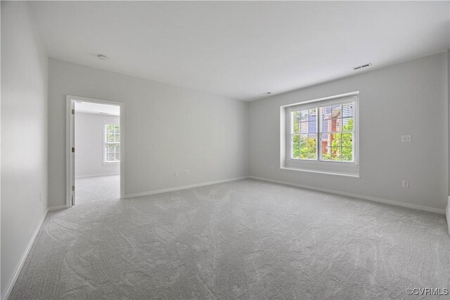 carpeted spare room featuring baseboards and visible vents