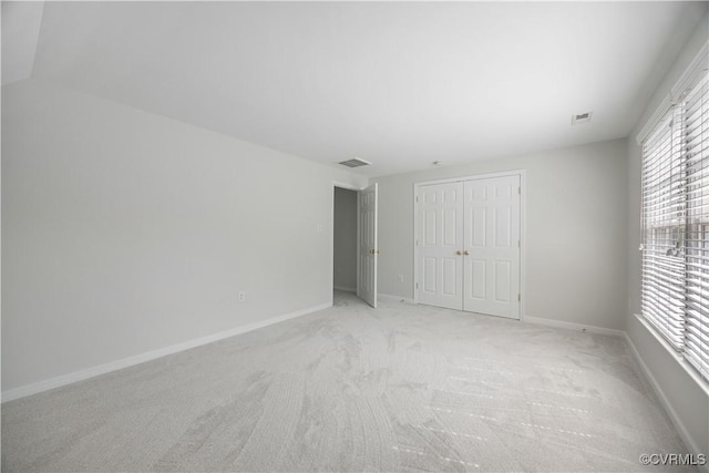 unfurnished bedroom with visible vents, a closet, baseboards, and light carpet