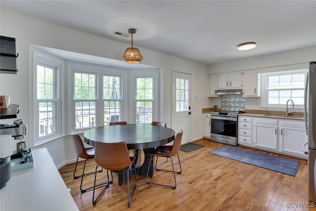 kitchen with visible vents, a healthy amount of sunlight, light wood-style floors, under cabinet range hood, and appliances with stainless steel finishes