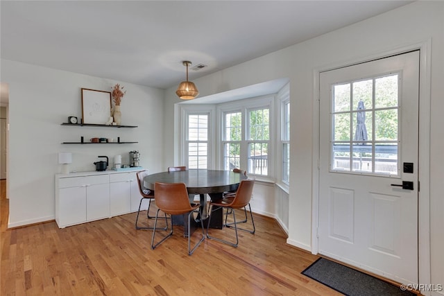 dining room with baseboards, visible vents, and light wood finished floors