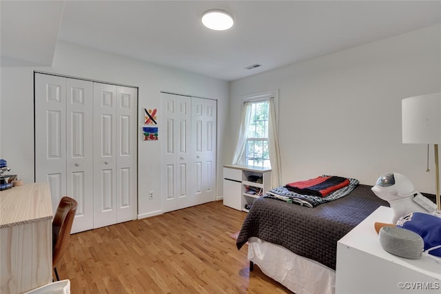 bedroom featuring light wood-style floors, multiple closets, and visible vents