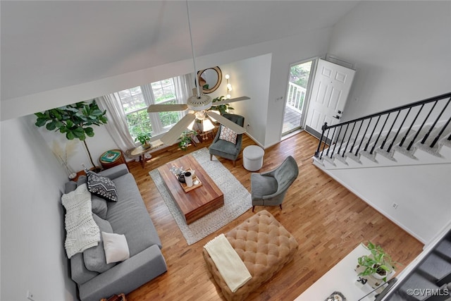 living room featuring a ceiling fan, baseboards, wood finished floors, and stairway