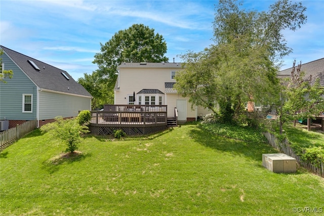 rear view of property featuring a lawn, fence, a deck, and cooling unit
