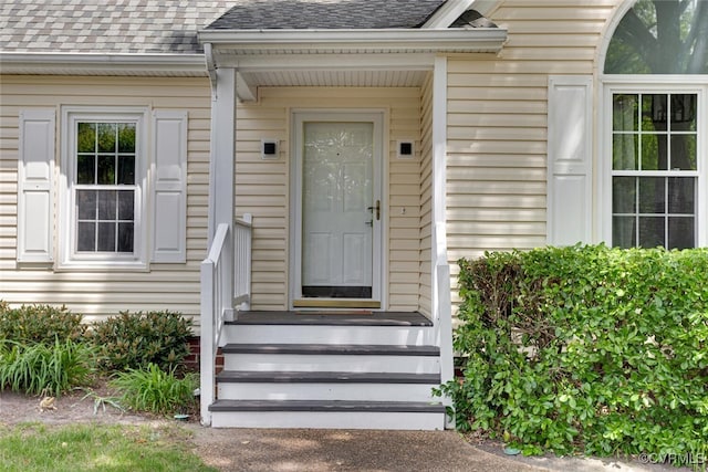 view of exterior entry featuring roof with shingles