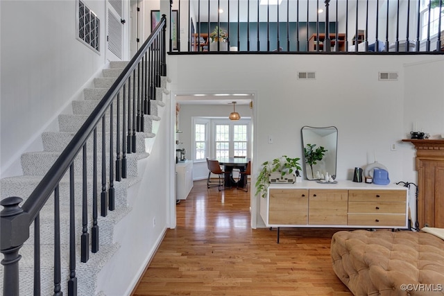 foyer entrance featuring light wood-style floors, a high ceiling, stairs, and visible vents