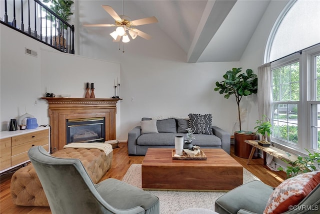 living room featuring high vaulted ceiling, visible vents, a wealth of natural light, and wood finished floors