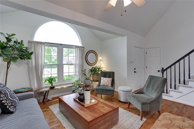 living area with stairway, high vaulted ceiling, a ceiling fan, and wood finished floors