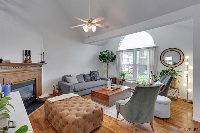 living area with ceiling fan, high vaulted ceiling, baseboards, a fireplace with flush hearth, and wood finished floors