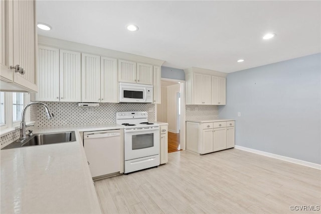 kitchen with tasteful backsplash, white appliances, light countertops, and a sink