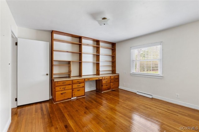 unfurnished office with dark wood finished floors, baseboards, baseboard heating, and built in study area